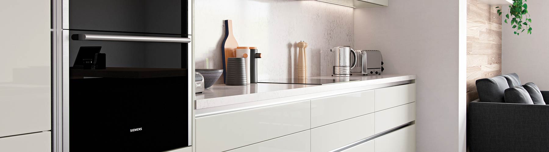 Gloss cream handle-less kitchen with white Corian worktop and integrated kitchen appliances.