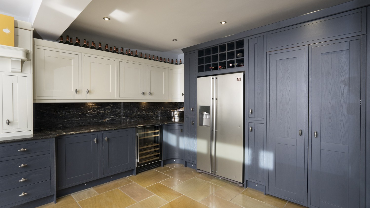 Timber inframe kitchen showing fridge/freezer and tall larder style cupboards. All units have been finished with a painted finish in midnight blue and Ivory.