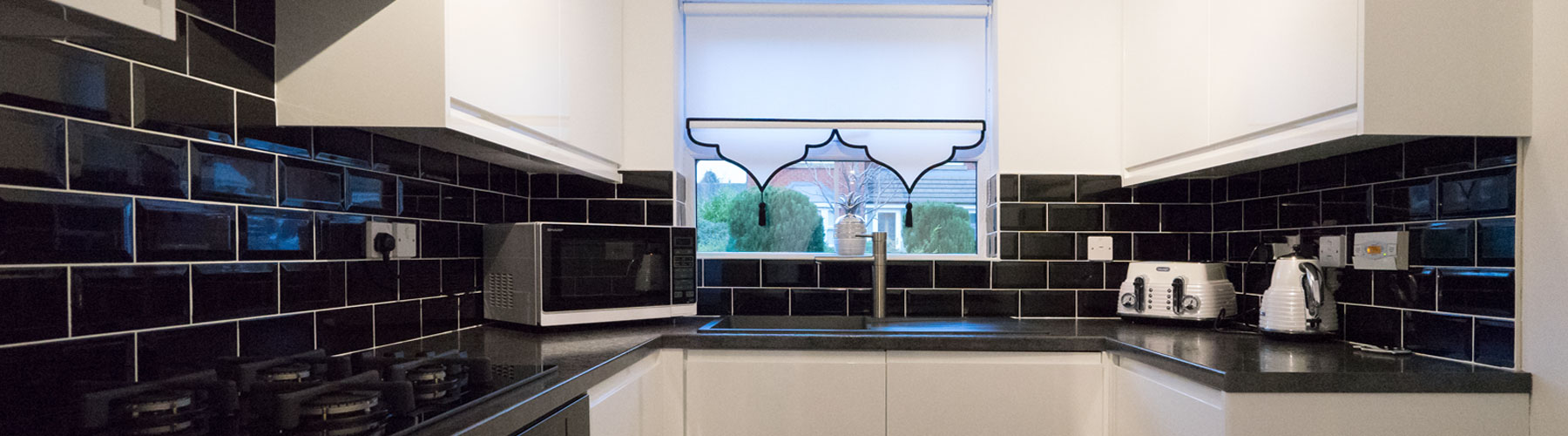 Gloss white handle-less kitchen with dark worktops.